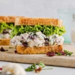 Cranberry pecan chicken salad inside a sandwich with lettuce.