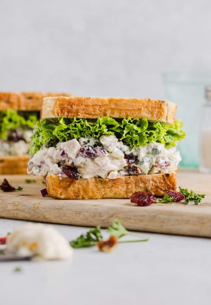 Cranberry pecan chicken salad inside a sandwich with lettuce.