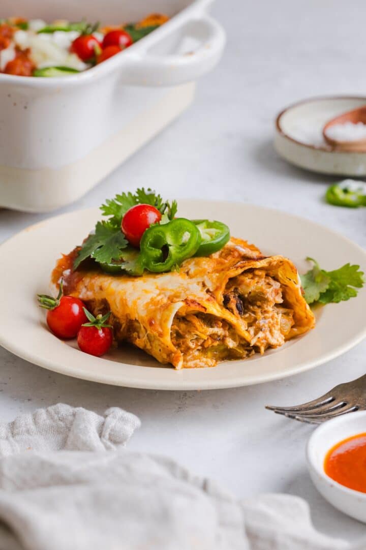 Two easy chicken enchiladas plated with sour cream and cilantro.
