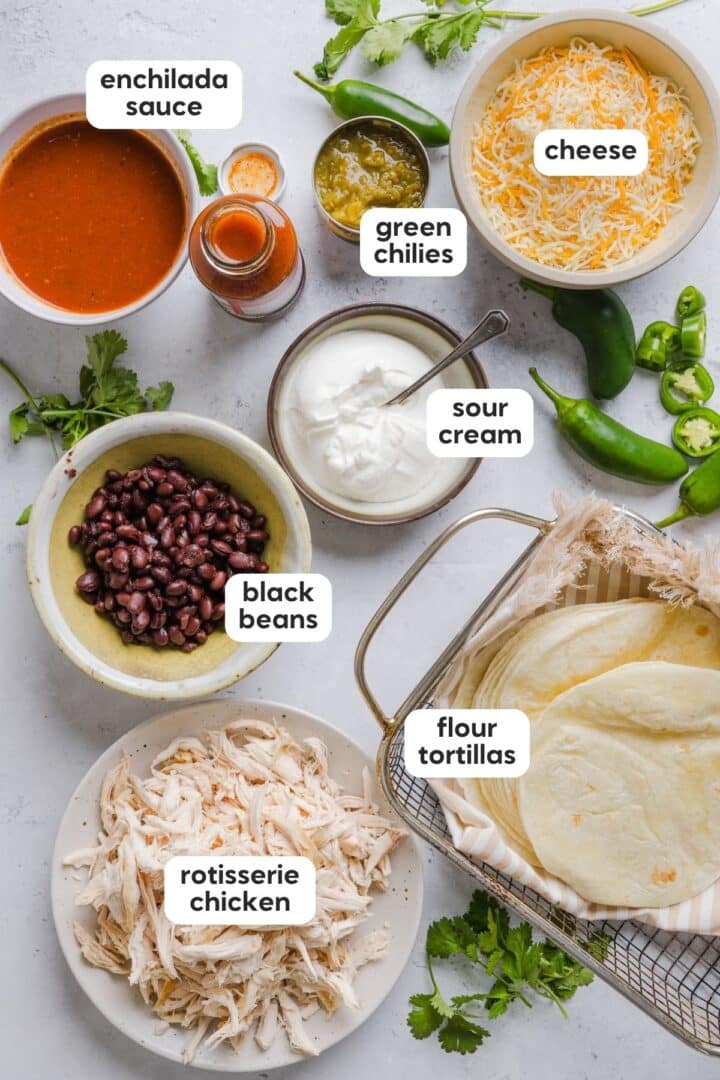 Ingredients for easy chicken enchiladas displayed in small bowls on a kitchen counter.