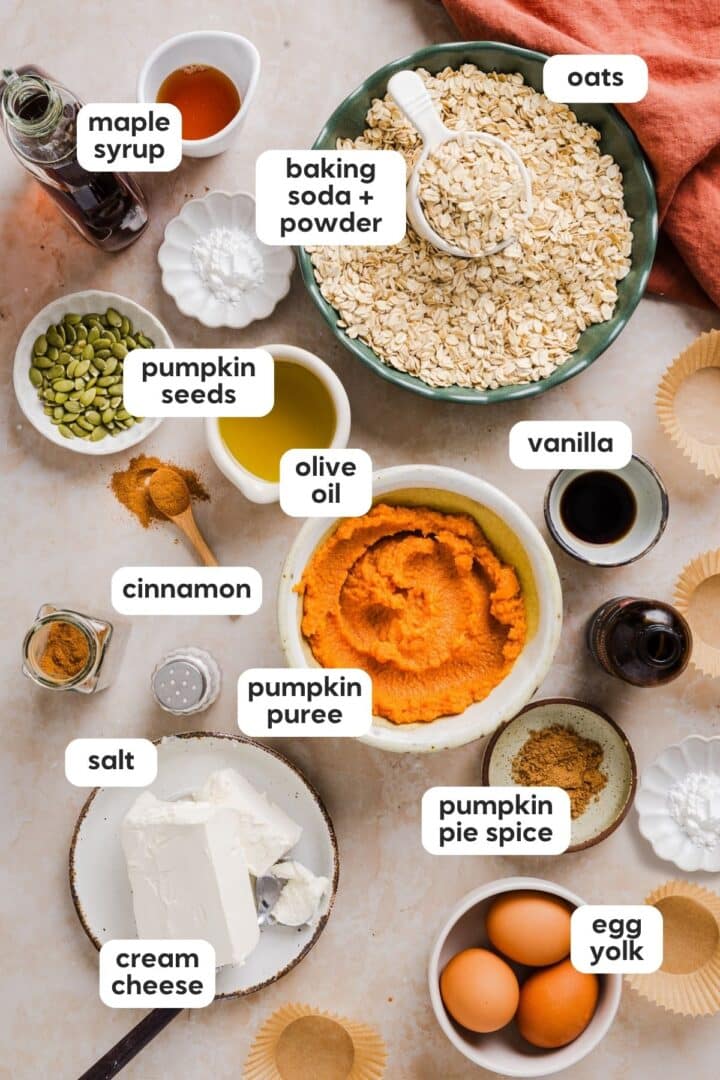Ingredients for pumpkin cream cheese muffins displayed in small bowls on a marble counter.