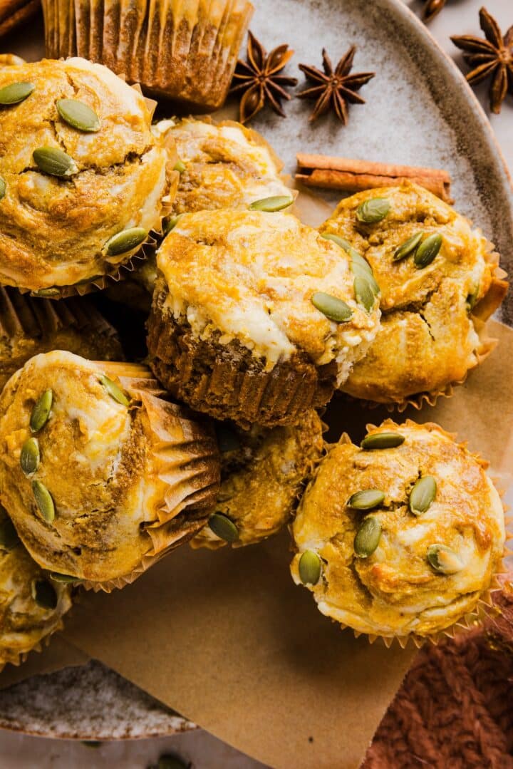 Pumpkin cream cheese muffins on a plate with pumpkin spice decor.