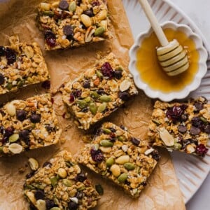 No-bake trail mix bars sliced and arranges on a parchment-lined plate with honey.