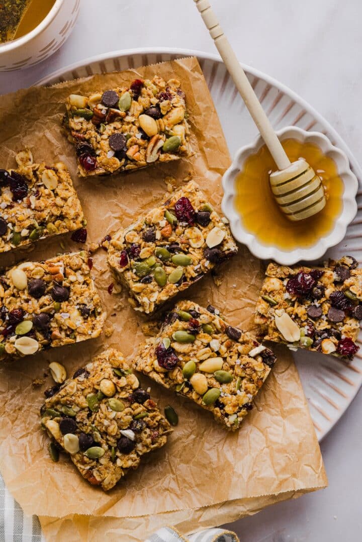 No-bake trail mix bars sliced and arranges on a parchment-lined plate with honey.