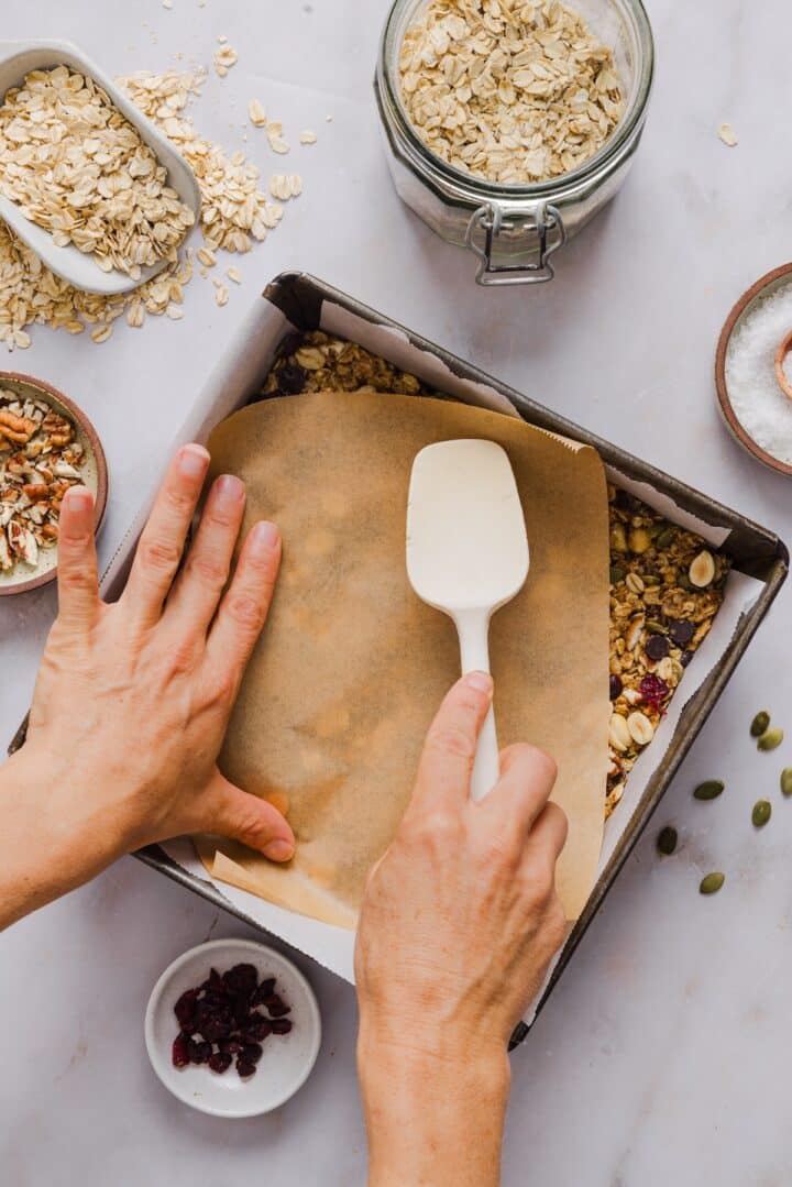 No-bake trail mix bars being pressed into a parchment-lined pan.