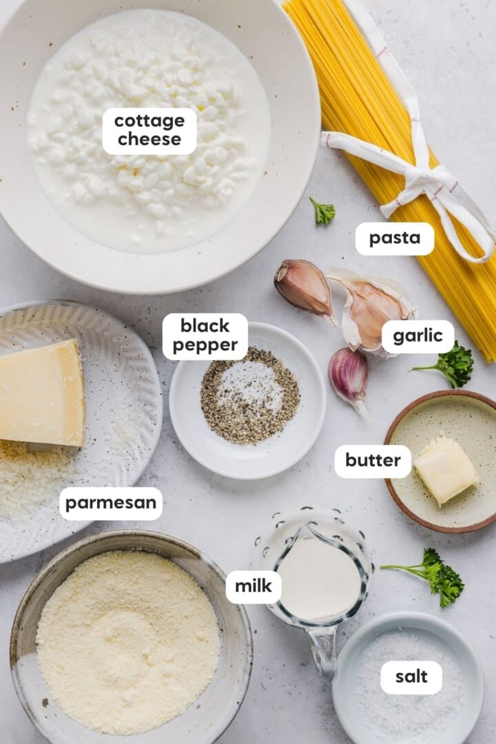 Ingredients for cottage cheese alfredo displayed in small bowls on a marble counter.