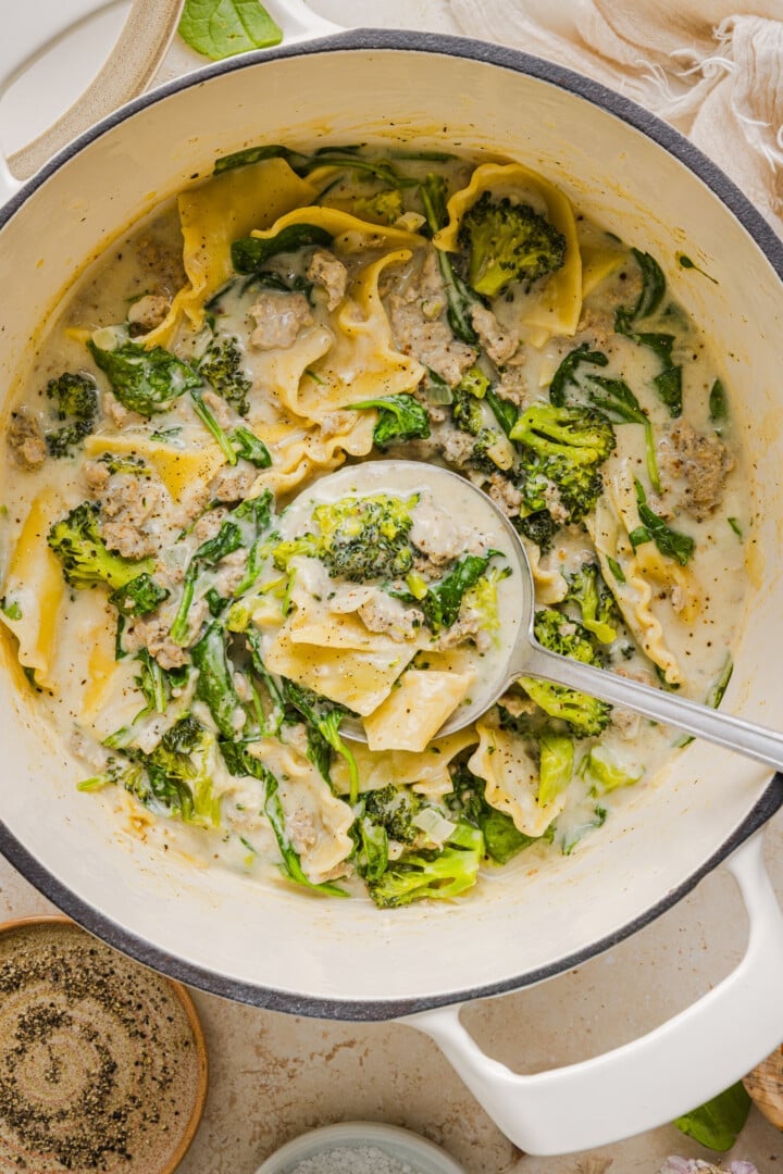 Creamy white lasagna soup in a large pot with a silver ladle. 