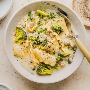 Creamy white lasagna soup in a white soup bowl with a spoon.