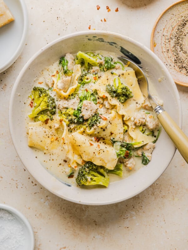 Creamy white lasagna soup in a white soup bowl with a spoon.