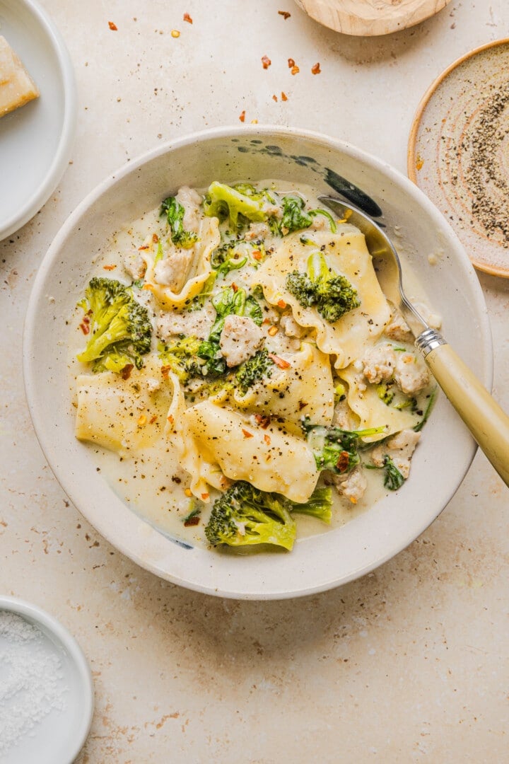 Creamy white lasagna soup in a white soup bowl with a spoon.