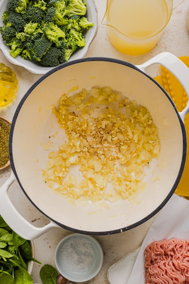 Chopped onions and garlic cooked in a large white pot.
