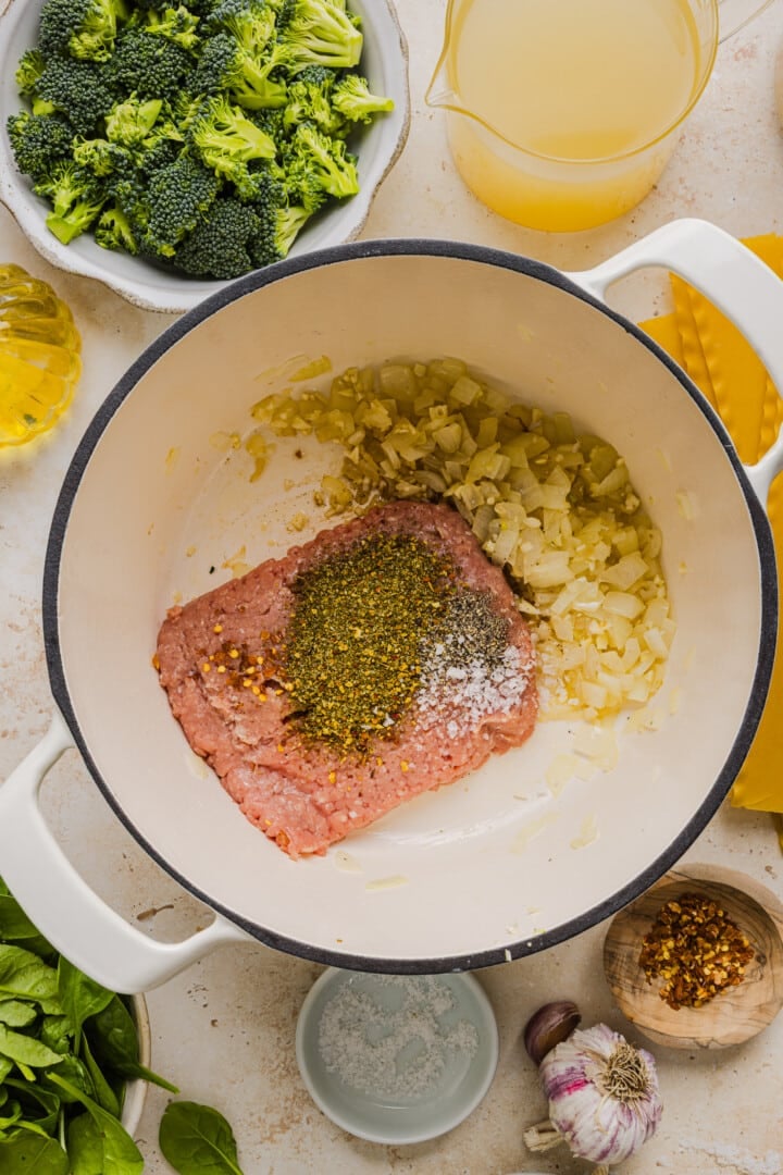 Ground chicken and spices in a large white pot.