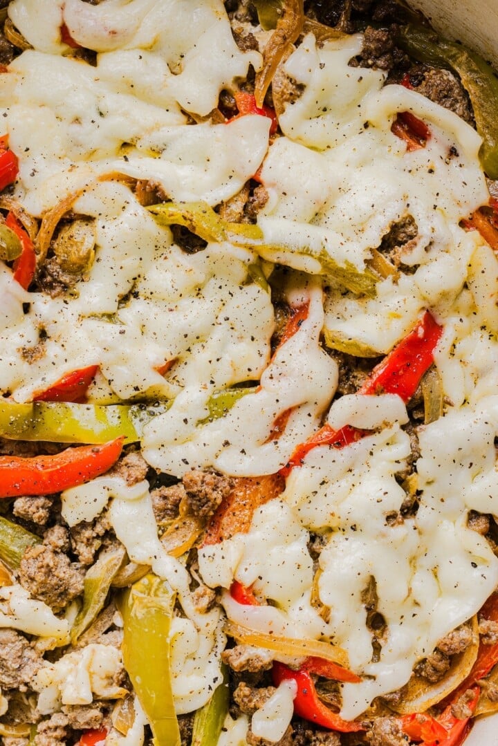 Melted cheese on top of a philly cheesesteak skillet.