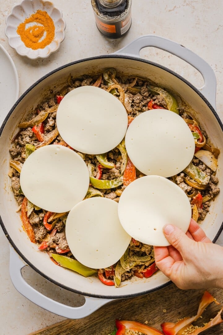 Provolone slices on top o philly cheesesteak skillet, before baking.