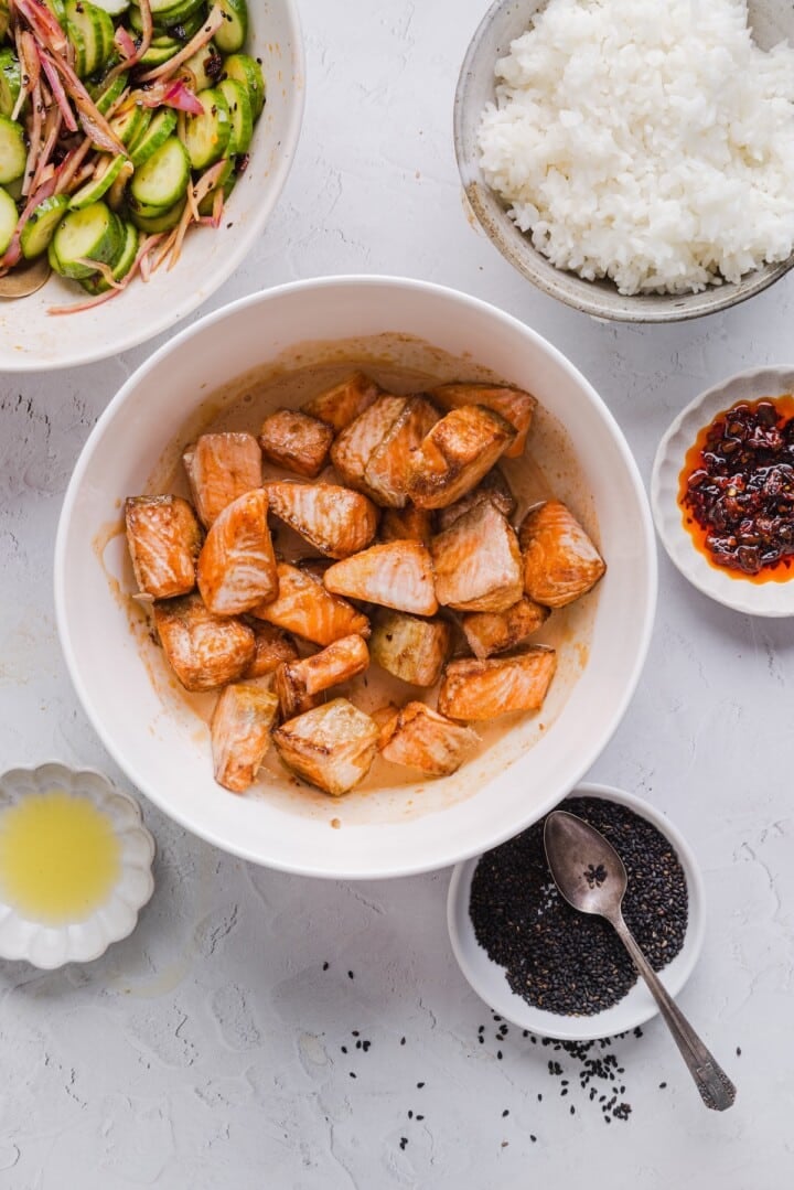 Salmon bites tossed in bang bang sauce in a white bowl.