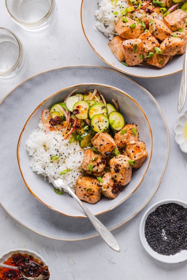 Salmon bites with cucumber salad and rice in a serving bowl.