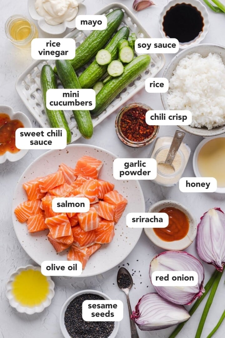 Ingredients and bang bang salmon bites displayed in small bowls on a marble counter.