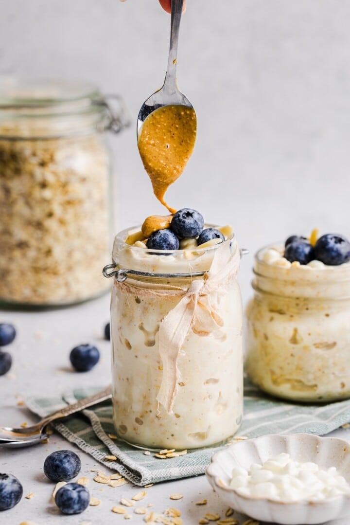 Cottage cheese overnight oats in a glass jar with peanut butter spooned on top.
