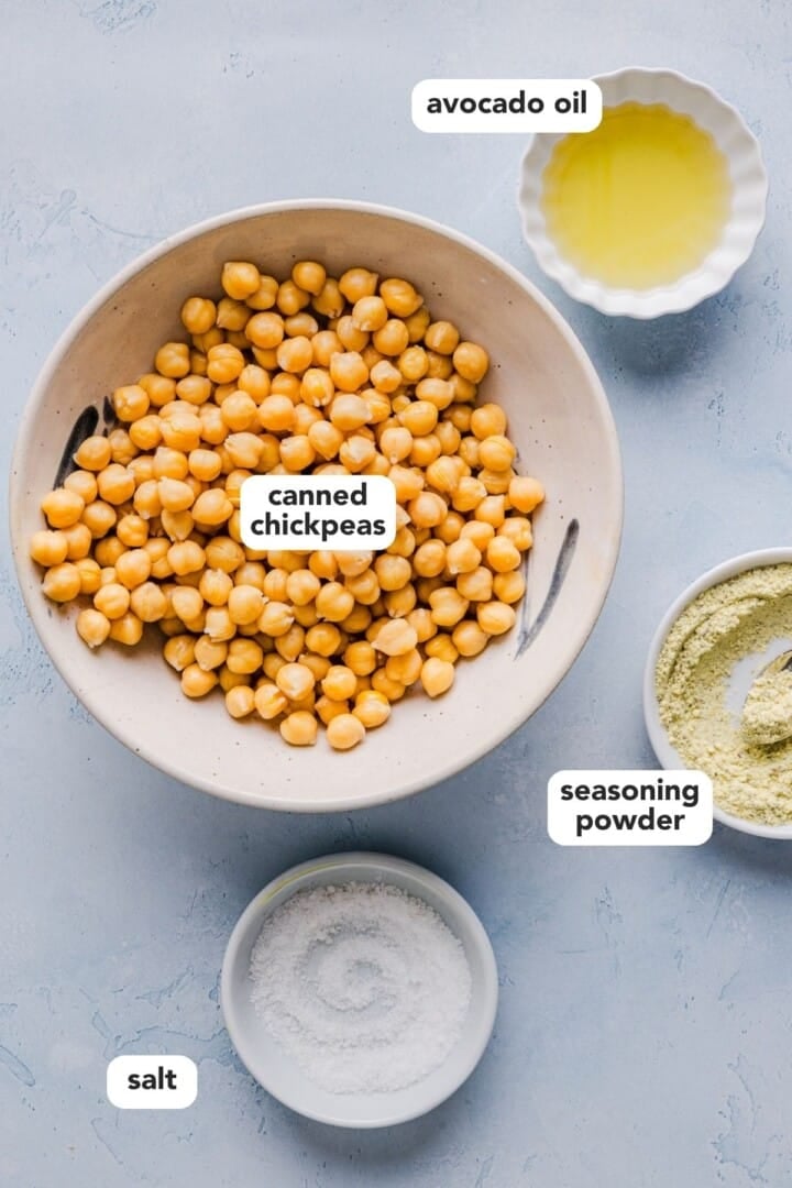 Ingredients for crunch roasted chickpeas displayed in small bowls on a light blue marble counter.