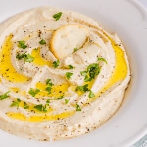High Protein hummus with cottage cheese displayed in a white bowl with pita chips.