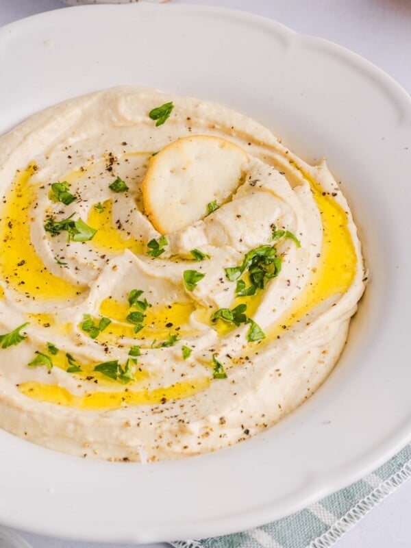 High Protein hummus with cottage cheese displayed in a white bowl with pita chips.