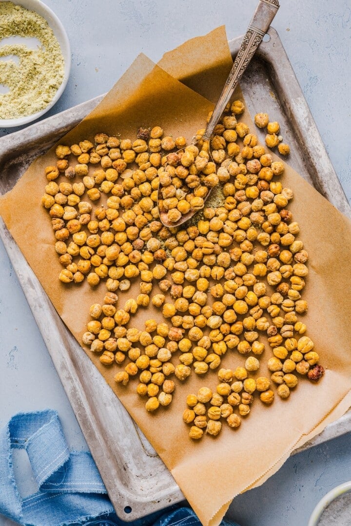 crispy roasted chickpeas on a parchment-lined pan with a silver spoon.