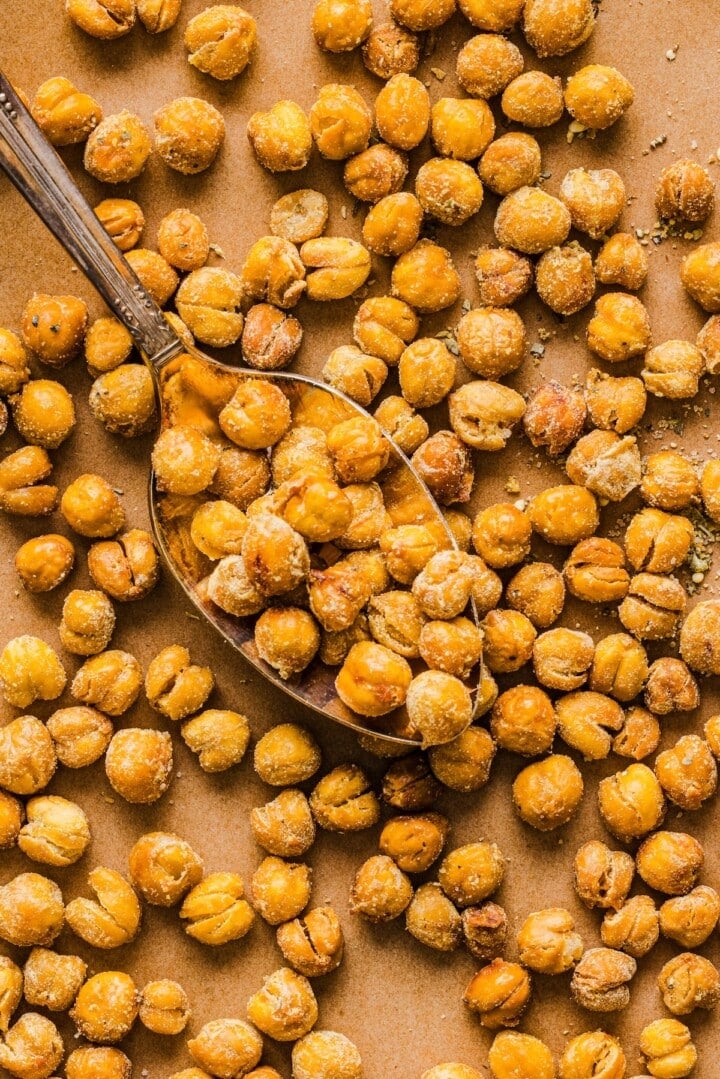 Crispy roasted chickpeas on parchment paper, with a silver spoon.