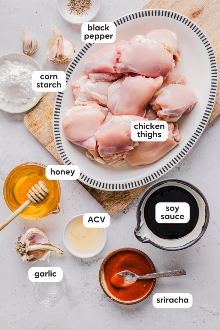Ingredients for slow cooker honey garlic chicken displayed in small bowls on a white counter.