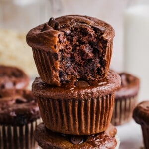 Three double chocolate cottage cheese muffins stacked on a marble counter.