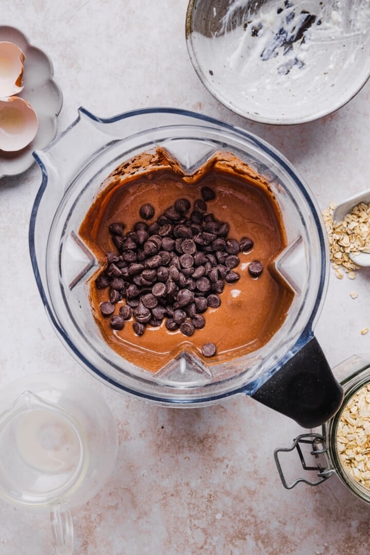 Chocolate chips getting stirred into muffin batter in a blender.