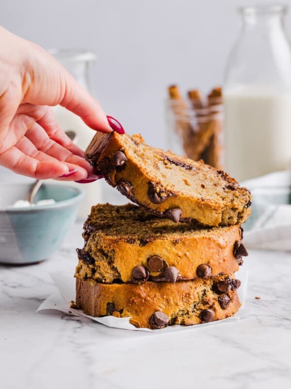 Three slices of cottage cheese banana bread with a woman's hand grabbing the top one.