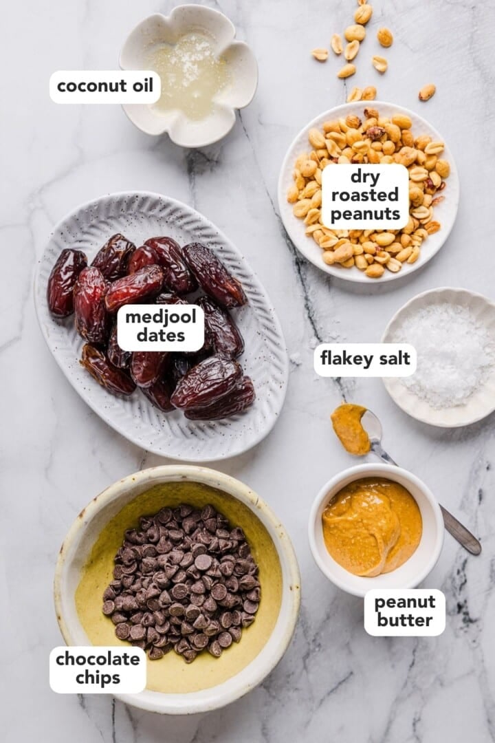 Ingredients for date bark displayed in small bowls on a marble counter.