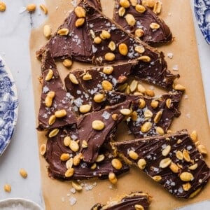 Sliced date bark with peanuts and chocolate on parchment paper.