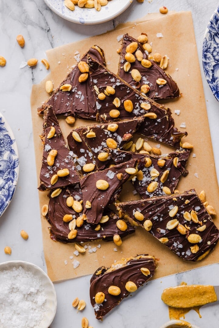 Sliced date bark with peanuts and chocolate on parchment paper.
