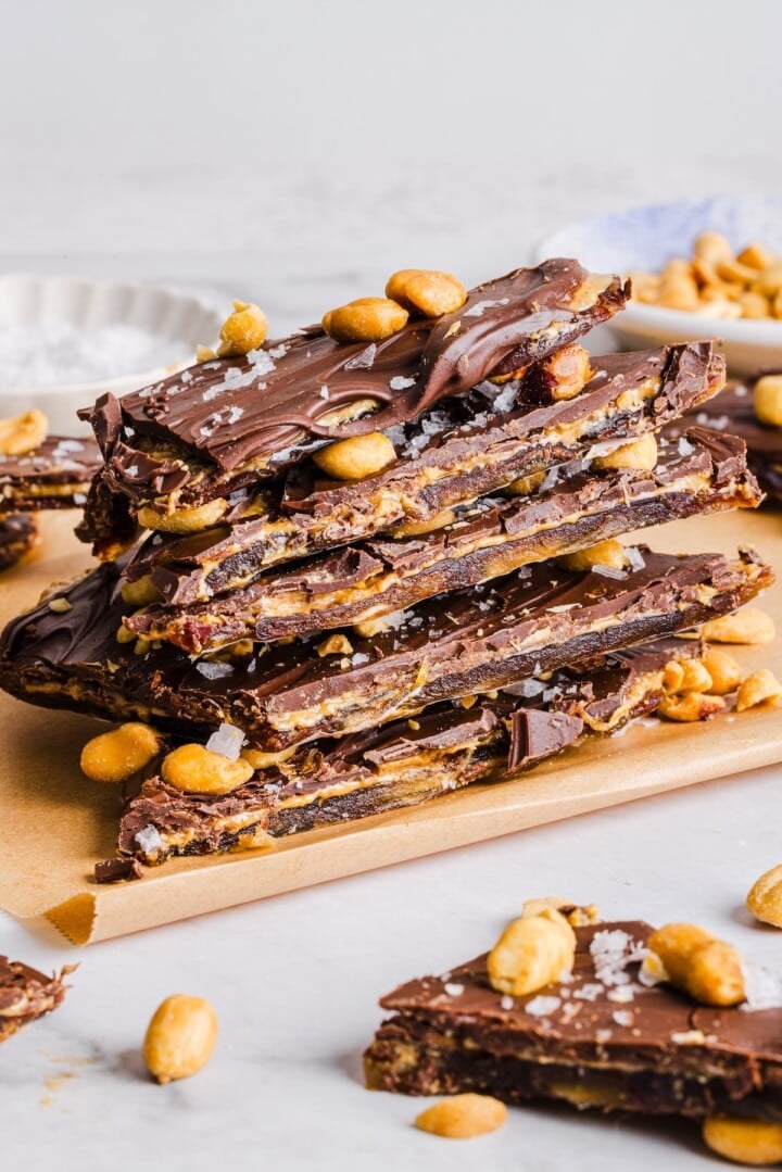 Sliced date bark piled on parchment paper, with chopped peanuts.