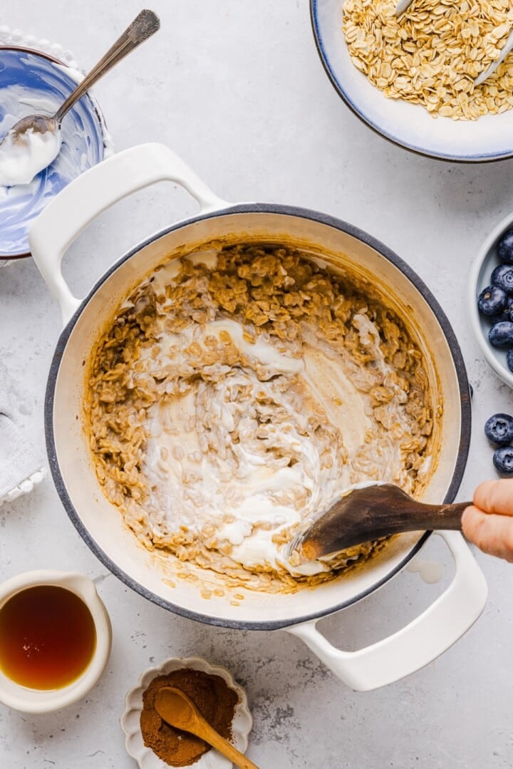 Greek yogurt being stirred into stovetop oatmeal.
