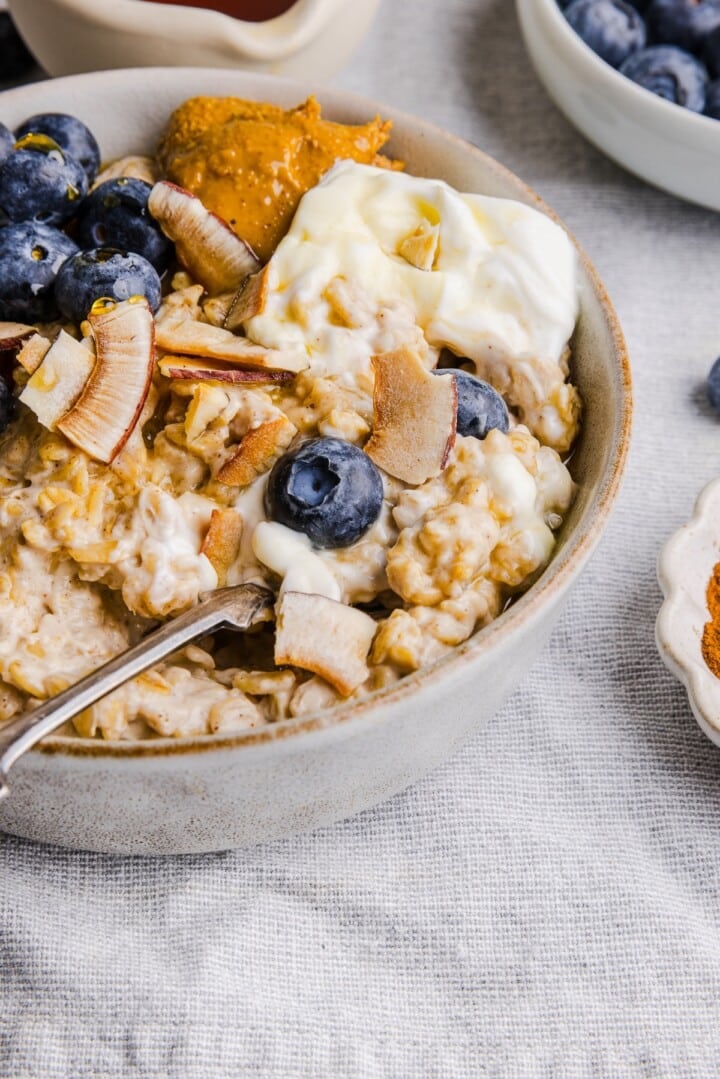 Close-up bowl of oatmeal with berries, coconut flakes, and greek yogurt.