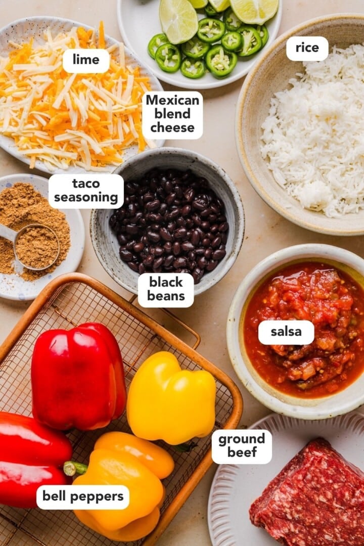 Ingredients for taco stuffed peppers displayed in small bowls on a beige kitchen counter.