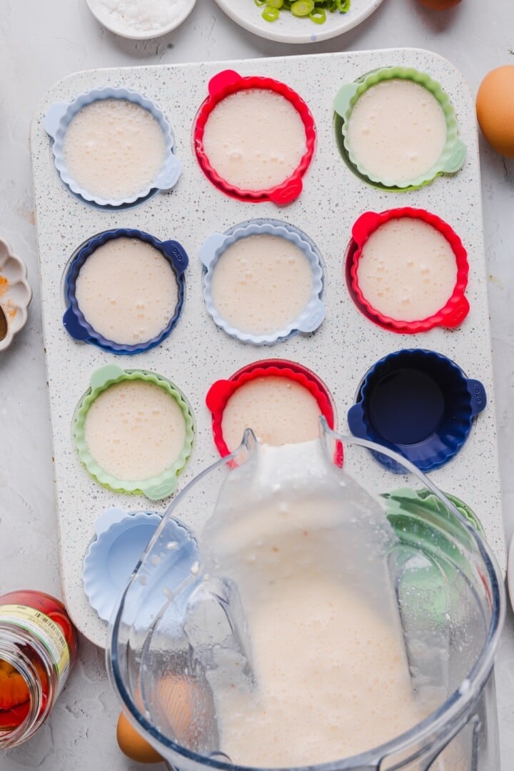 Egg white bites batter being poured into prepared muffin pan with silicone liners.