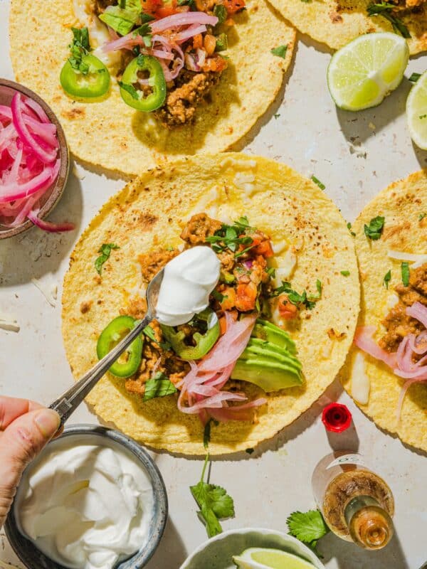Hand adding toppings to the easy ground turkey tacos.