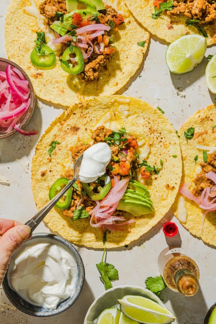 Hand adding toppings to the easy ground turkey tacos.