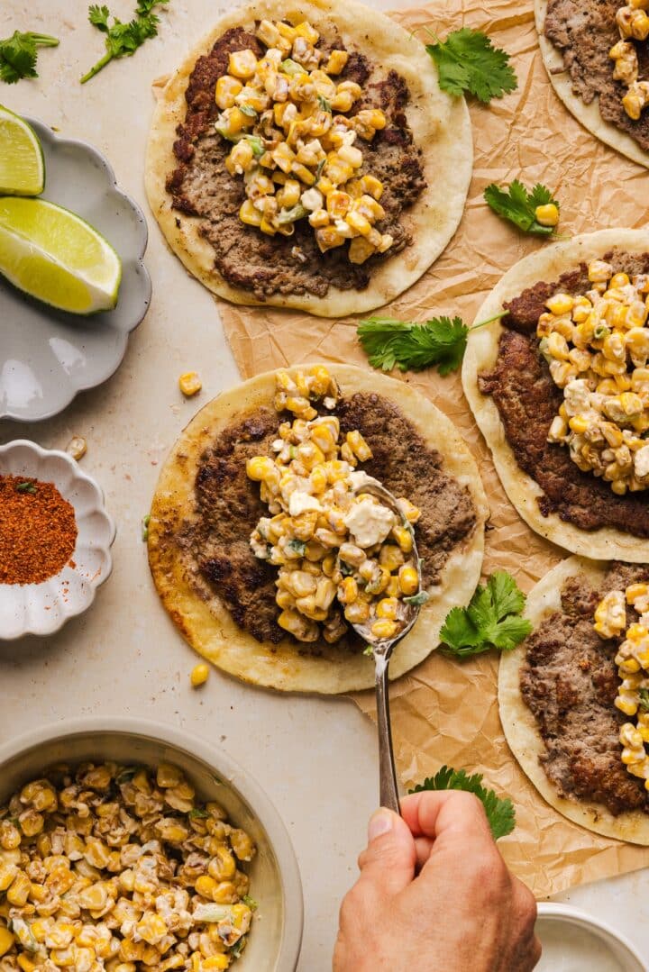 Birdseye of adding elote topping to street corn tacos.