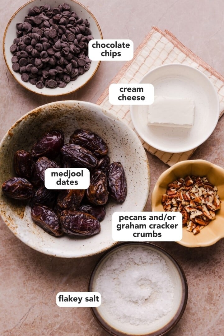 Ingredients for cheesecake stuffed dates displayed in small bowls on a marble counter