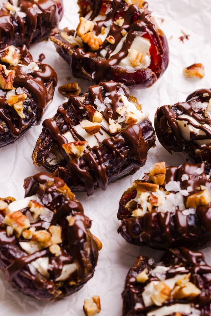 cheesecake stuffed dates with melted chocolate and chopped pecans.