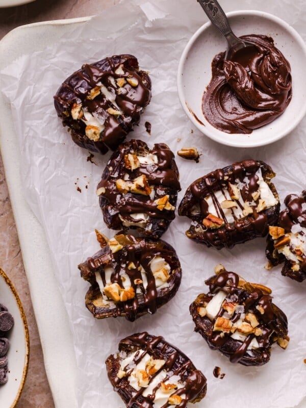 Cream cheese stuffed dates topped with drizzled chocolate on parchment paper.