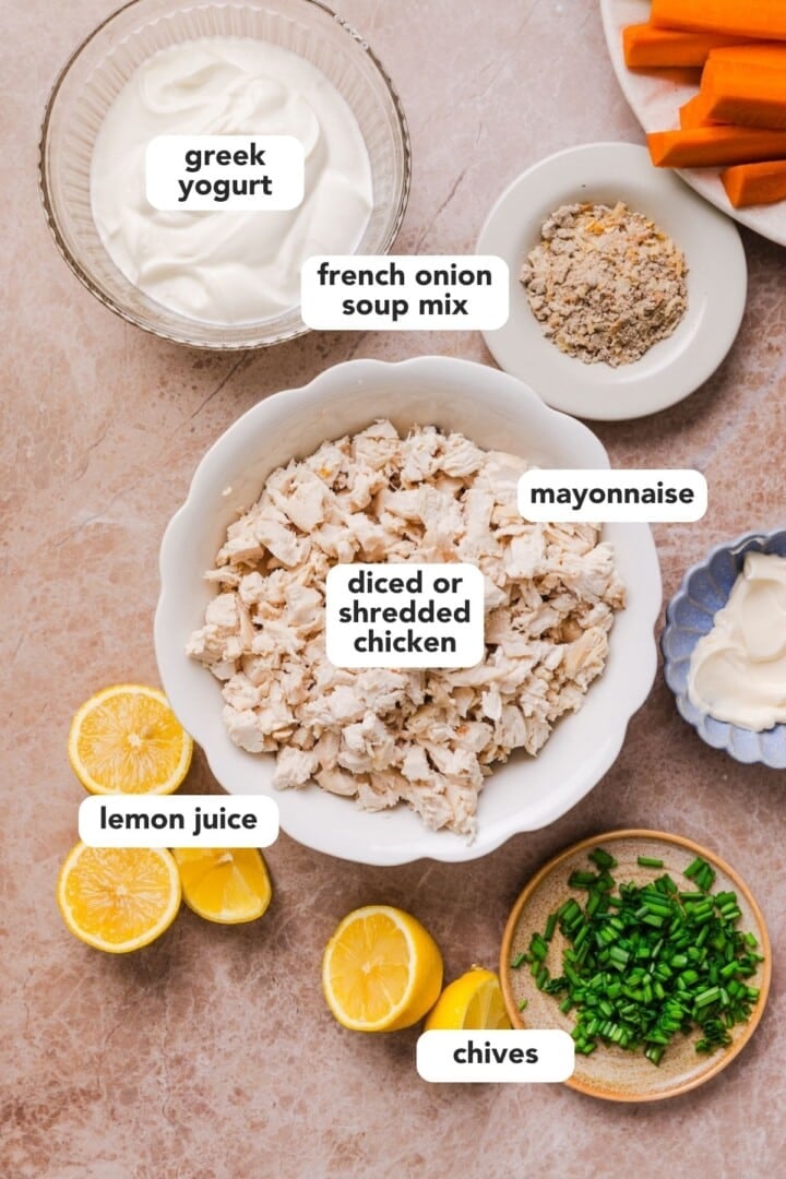 Ingredients for high-protein french onion chicken salad in bowls on a marble counter.