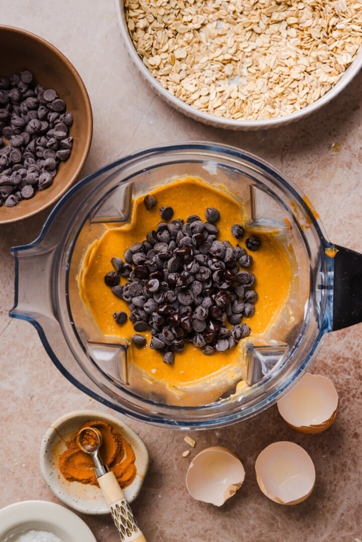 Chocolate chips poured into pumpkin muffin batter in a blender