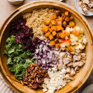 Deconstructed fall harvest quinoa salad in a large wooden mixing bowl.