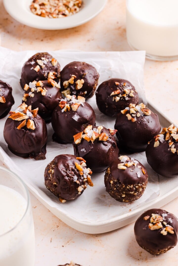 Pecan Pie Energy Bites on a white plate, covered in chocolate.