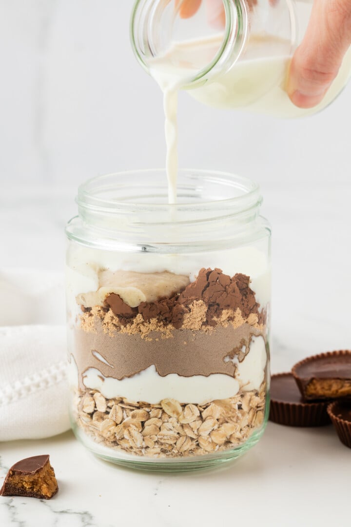 Ingredients for chocolate peanut butter overnight oats poured in a glass jar.